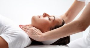 chiropractor's hands laid on female patient's neck and shoulders