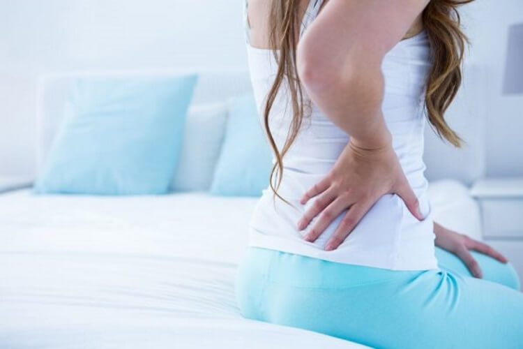 woman sitting on the bed having low back pain